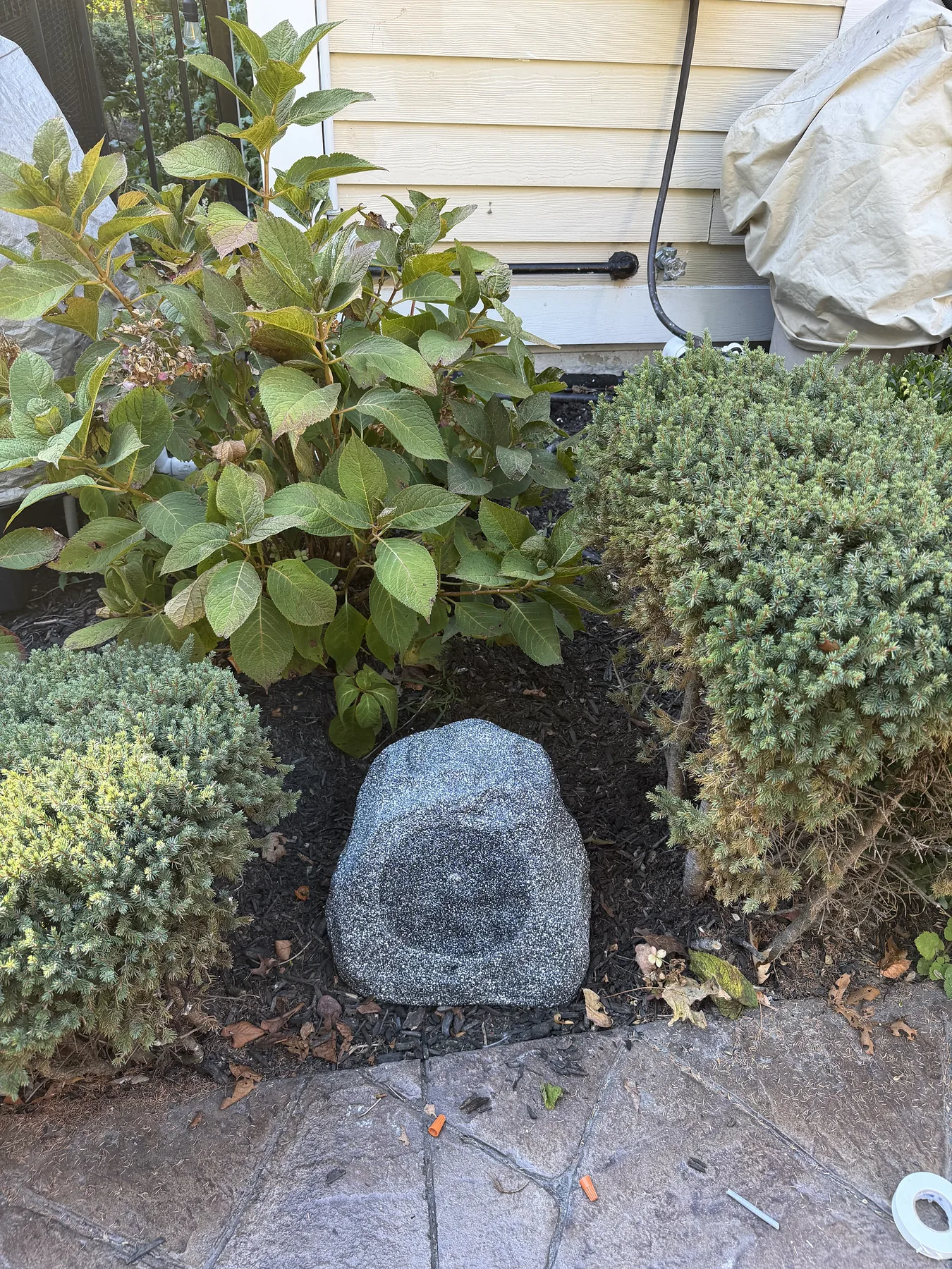 Outdoor rock-style landscape speaker installed in a garden bed