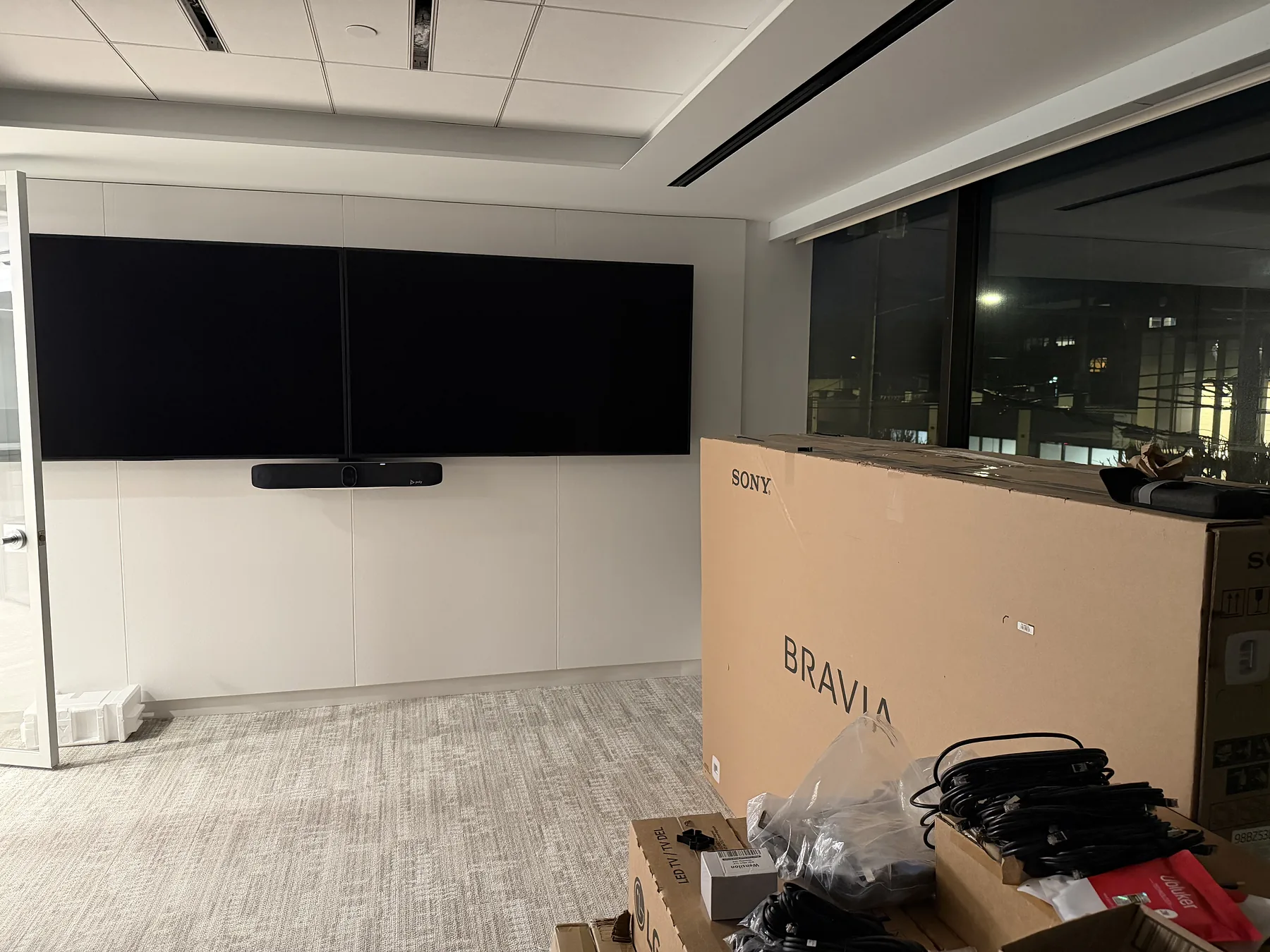 Dual wall displays being set up with TV shipping box on floor