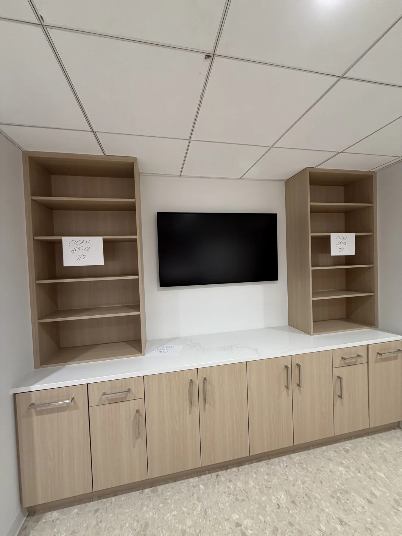 Television built into light wood office cabinetry