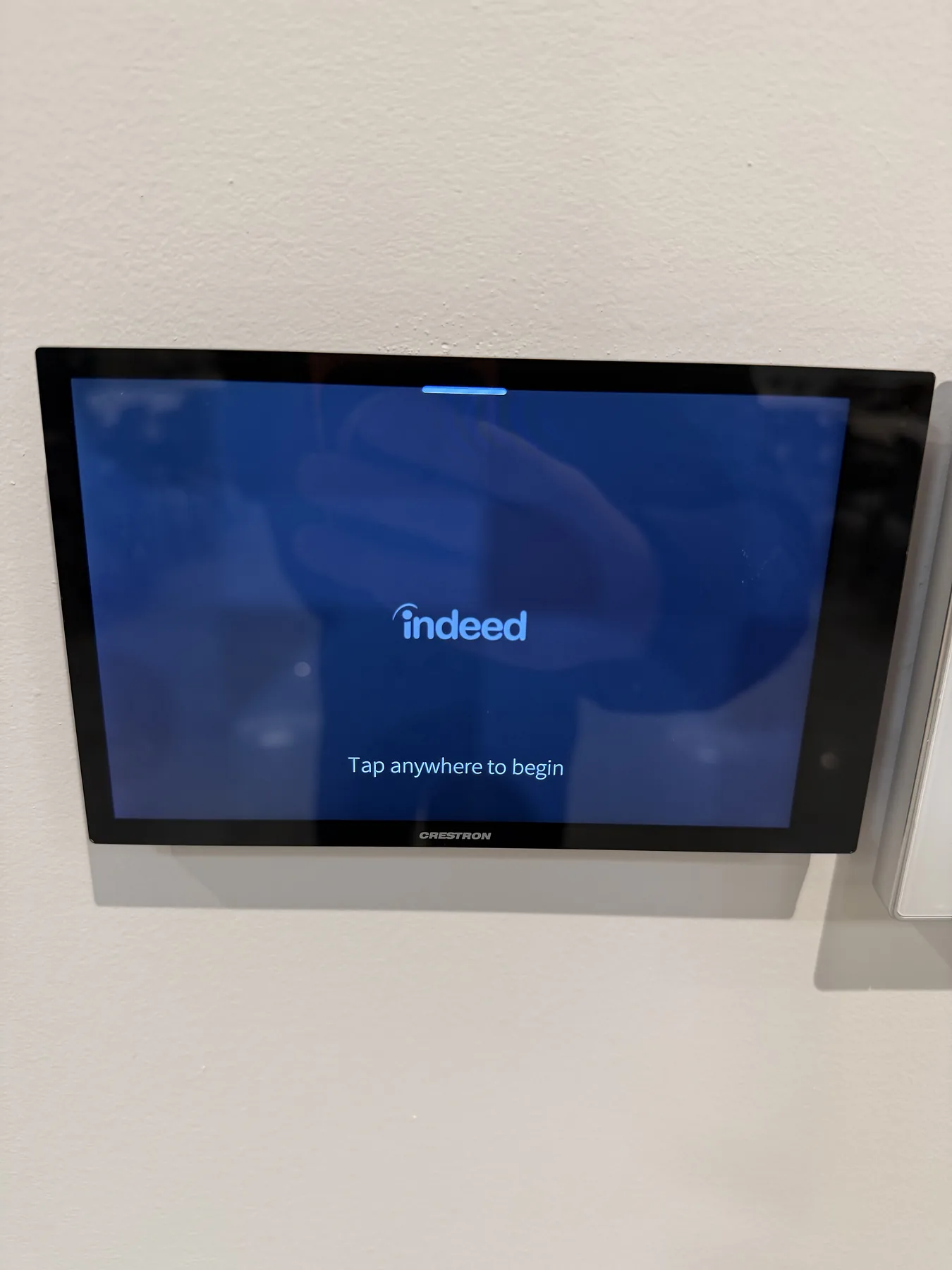 Wall-mounted Crestron touchscreen control panel for room entry