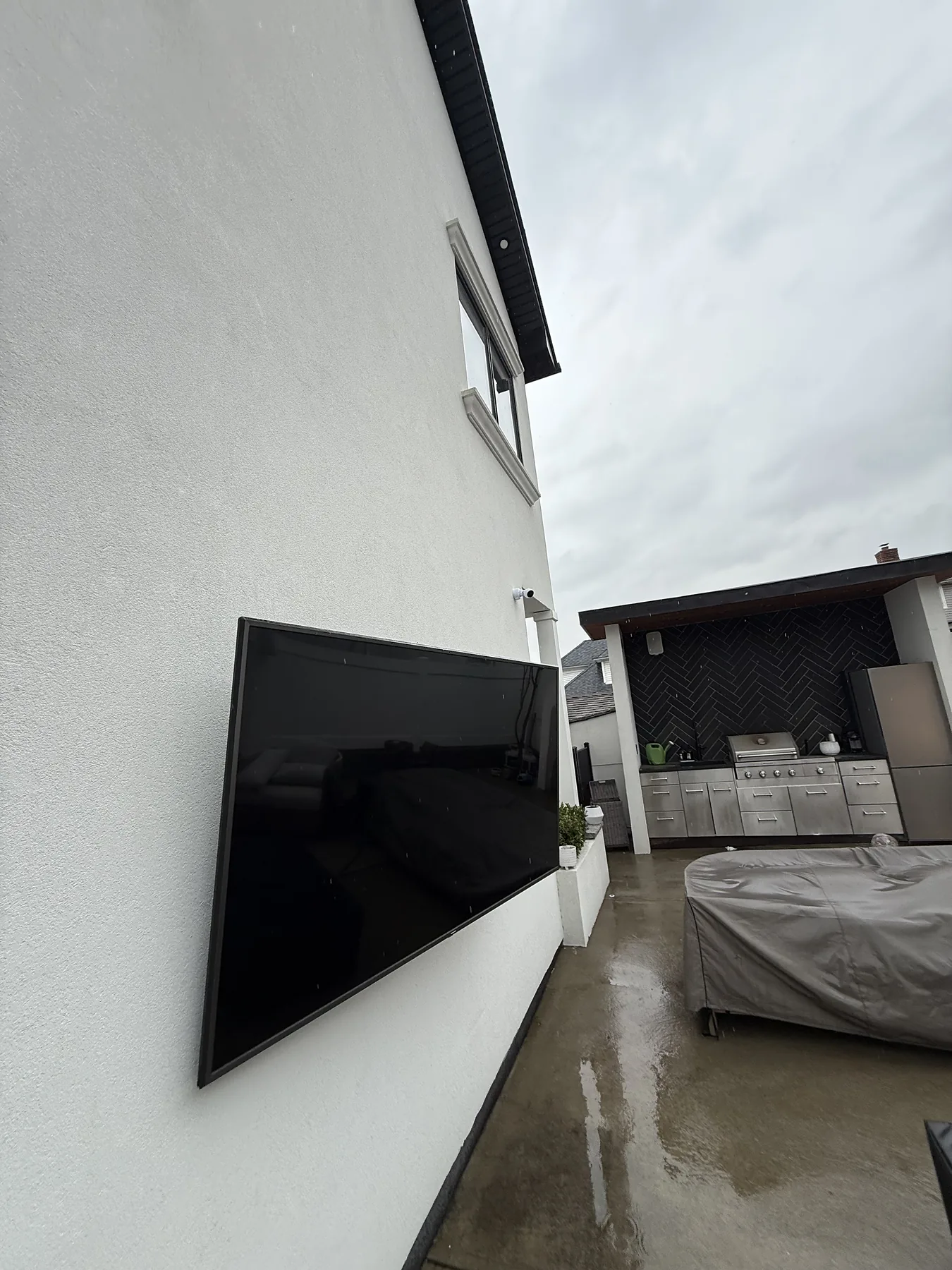Large outdoor television mounted on a white exterior wall