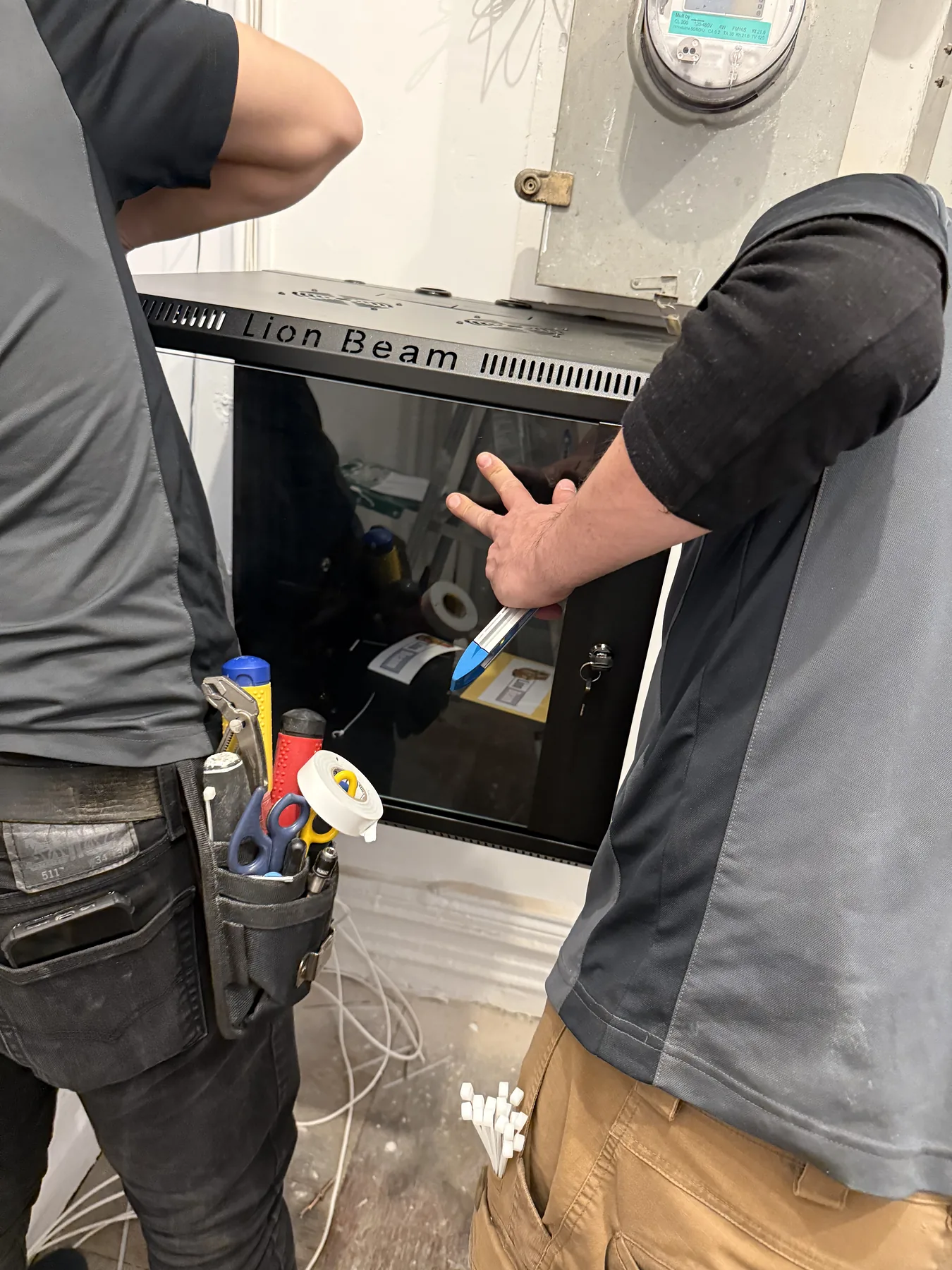 Technicians working on equipment inside a dark cabinet enclosure