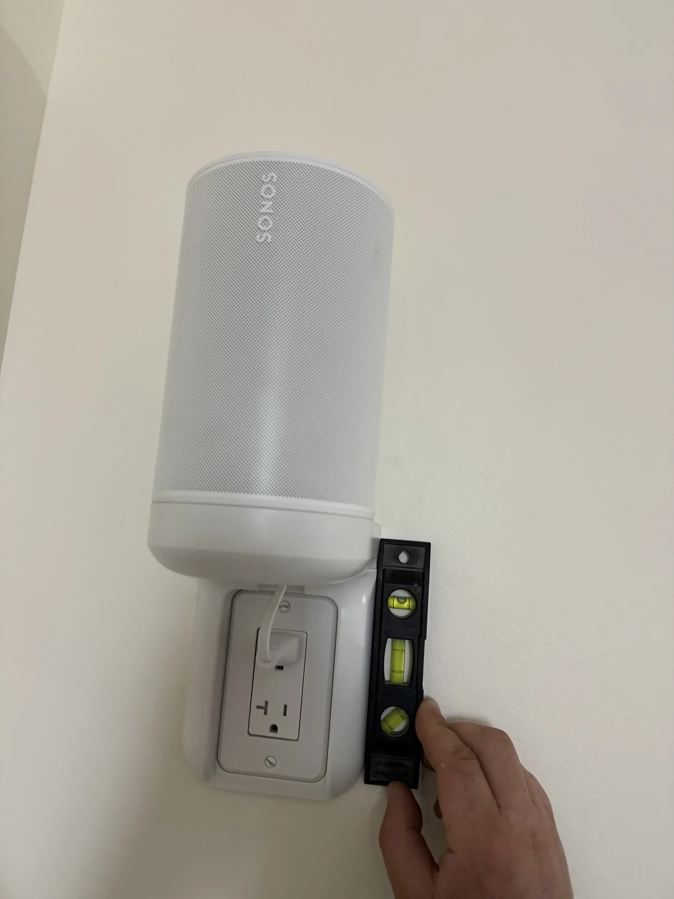 Wall-mounted cylindrical speaker leveled during installation