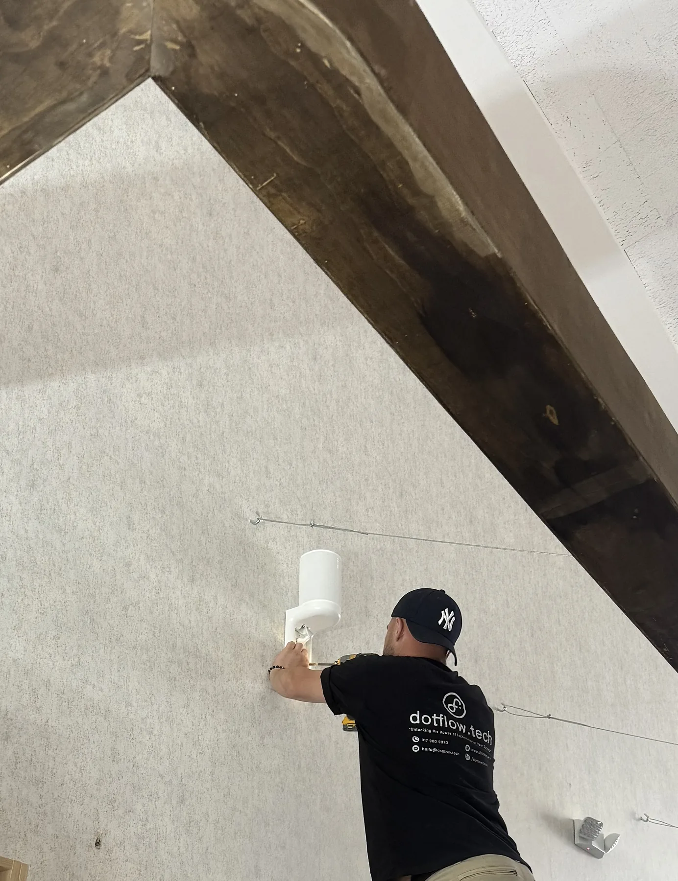 Technician wall-mounting a cylindrical speaker or wireless AV device