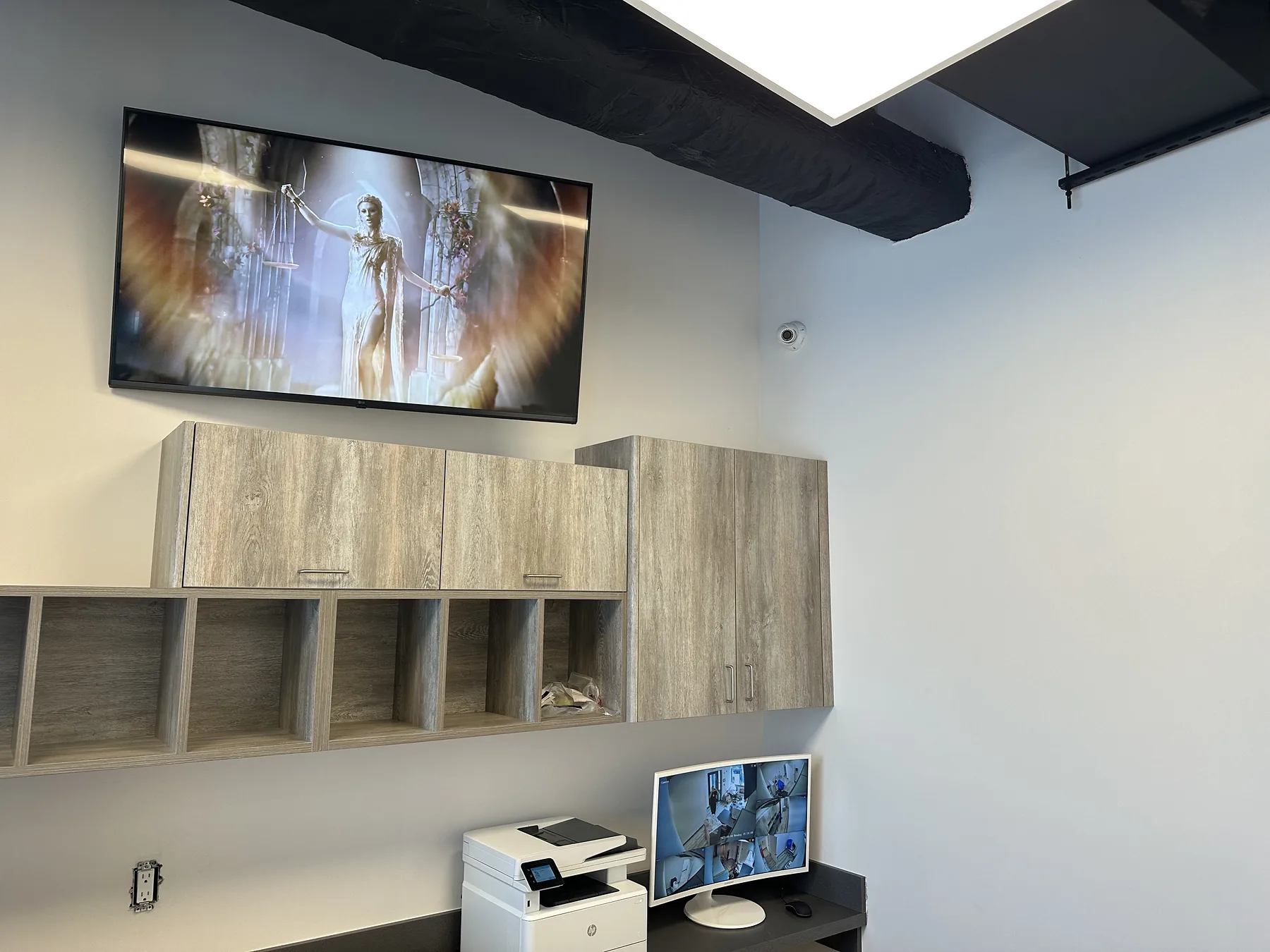 Finished office wall with mounted TV, shelves, and workstation