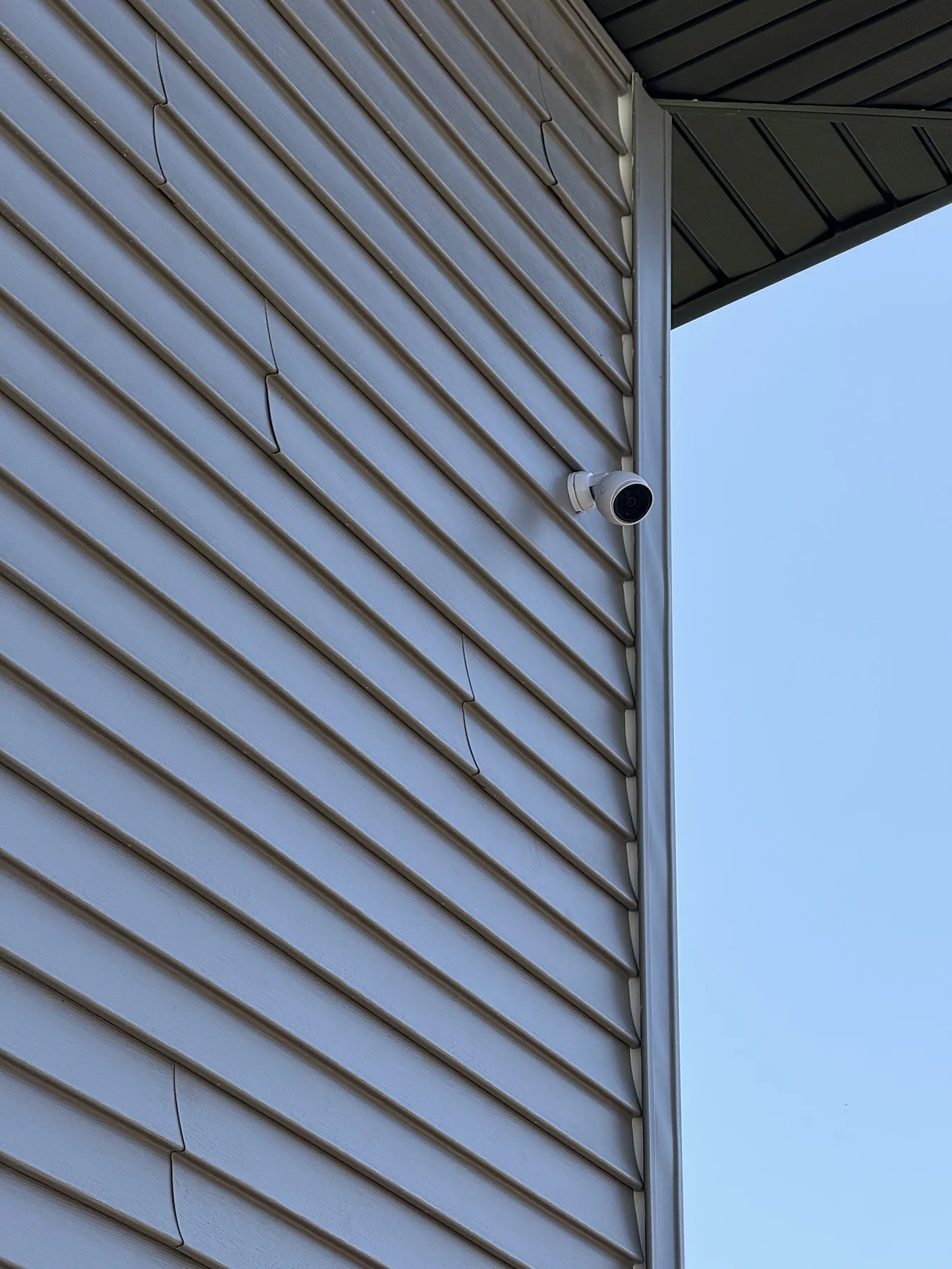 White dome security camera on grey house siding