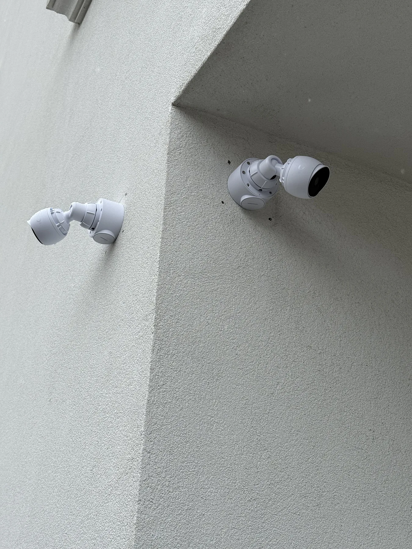 Two white bullet security cameras on an exterior corner