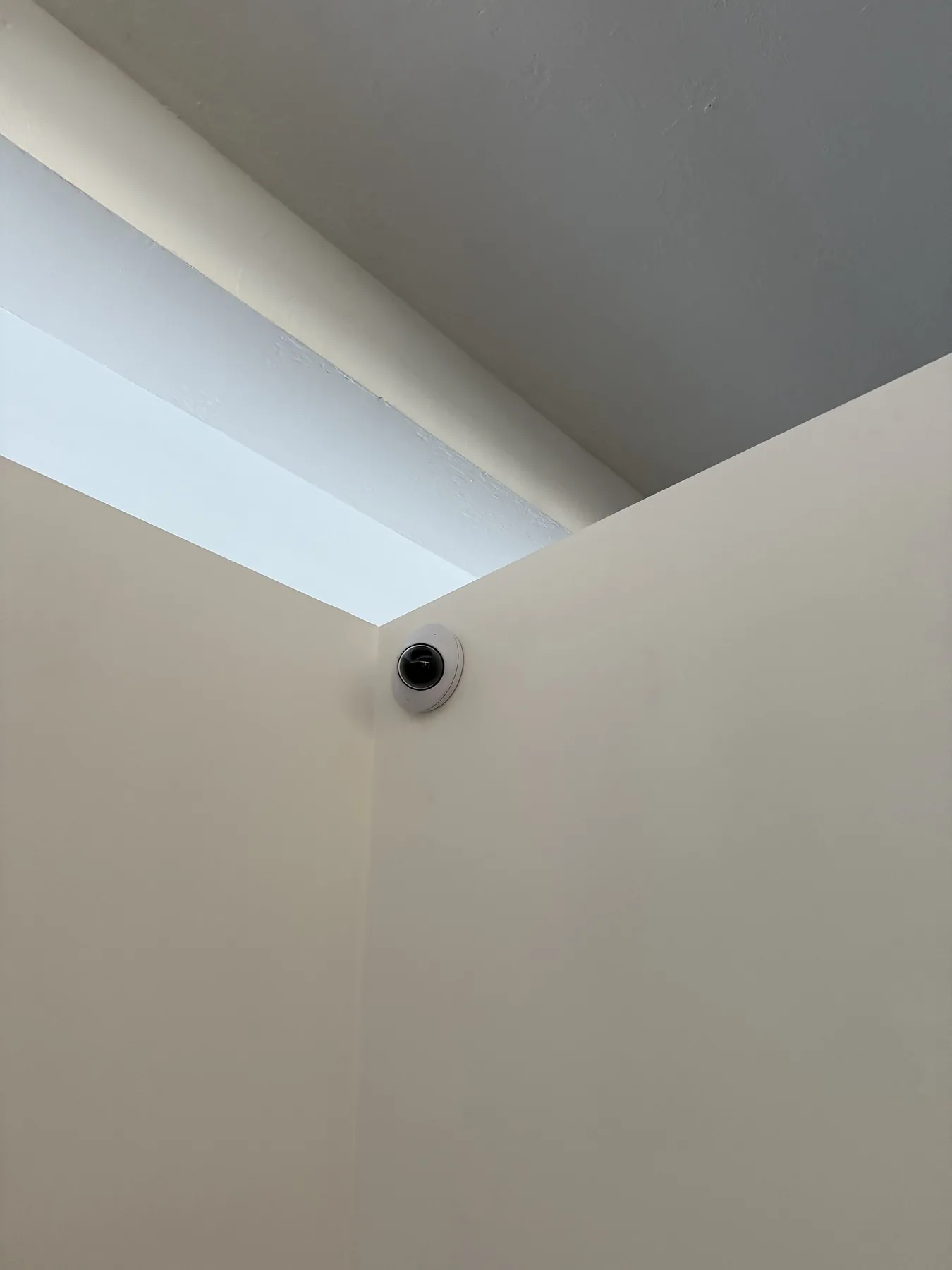 Small black circular camera lens mounted on a white wall