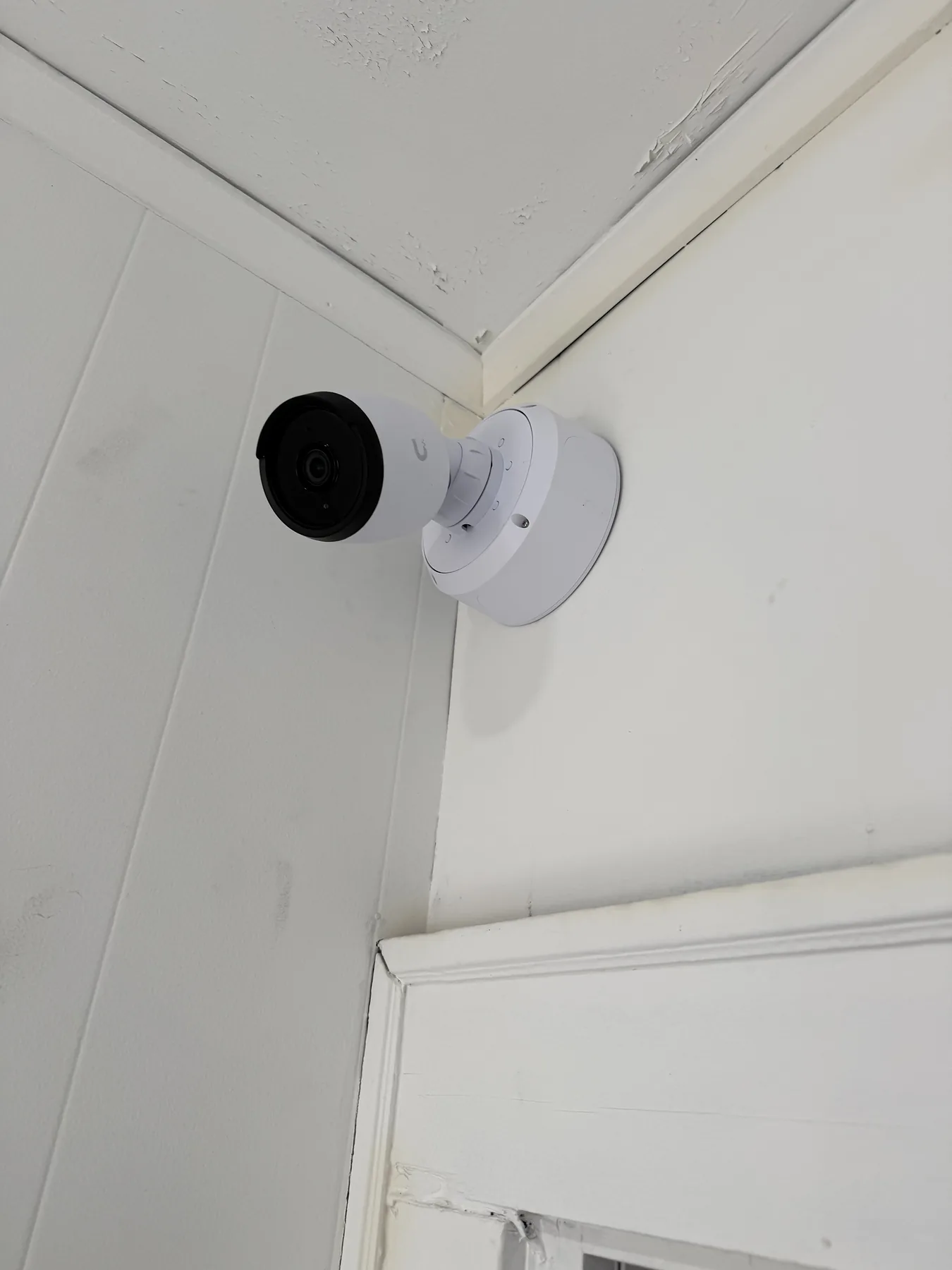 White bullet security camera mounted high on a corner