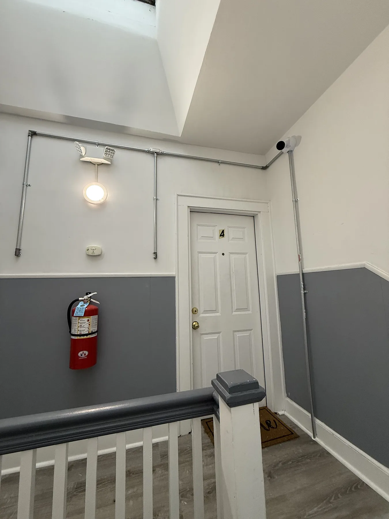 Hallway with fire extinguisher and metal conduit toward a door