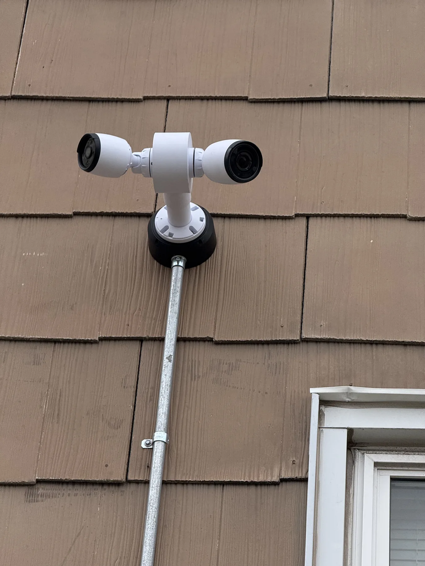 Outdoor dual bullet security cameras with conduit on wood siding