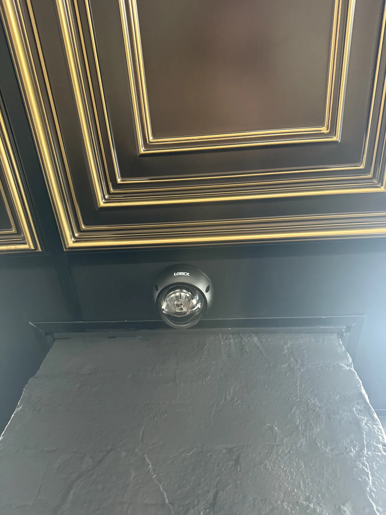 Glass-domed ceiling fixture or sensor near decorative trim