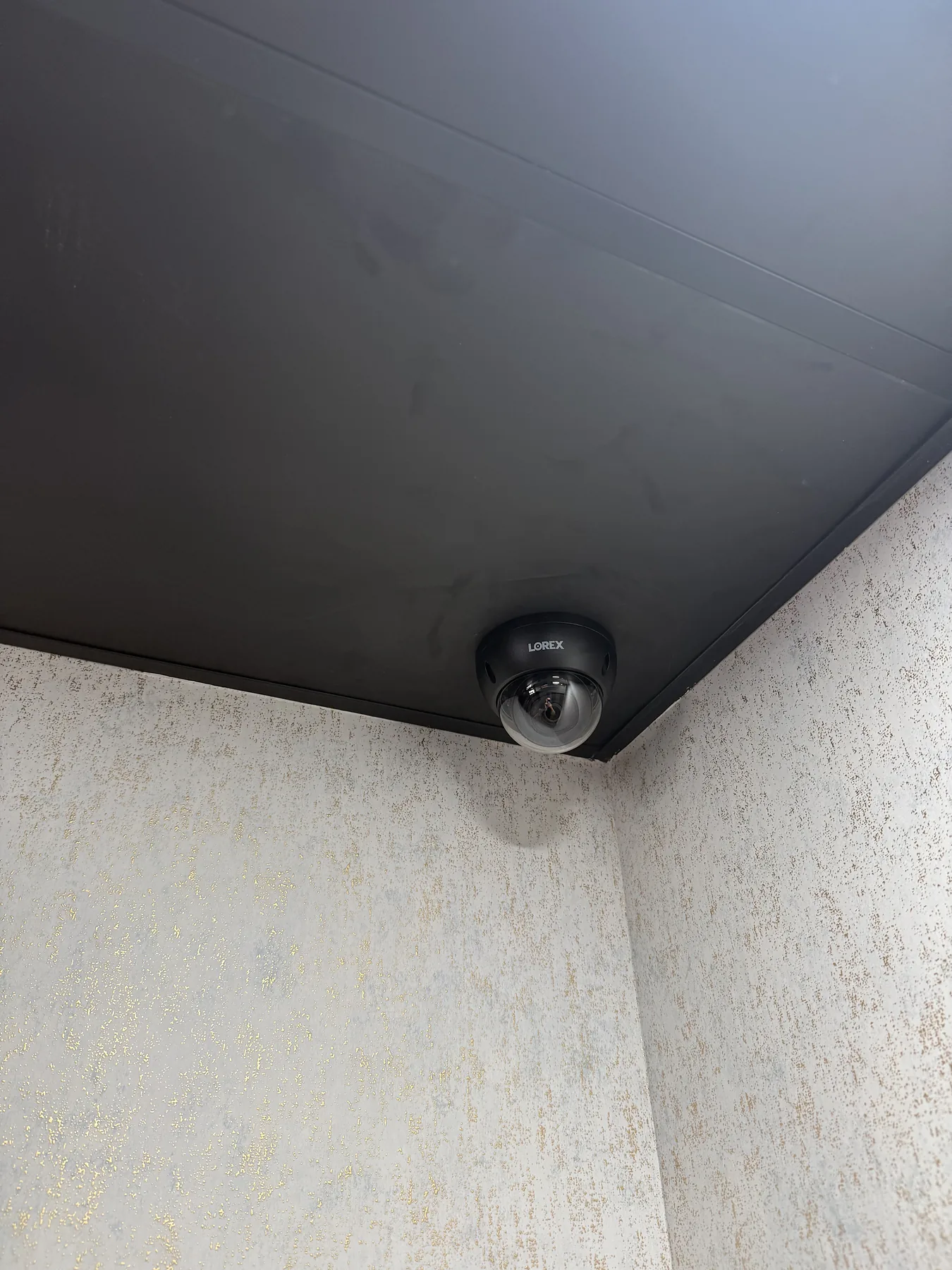 Black dome security camera at a dark ceiling corner