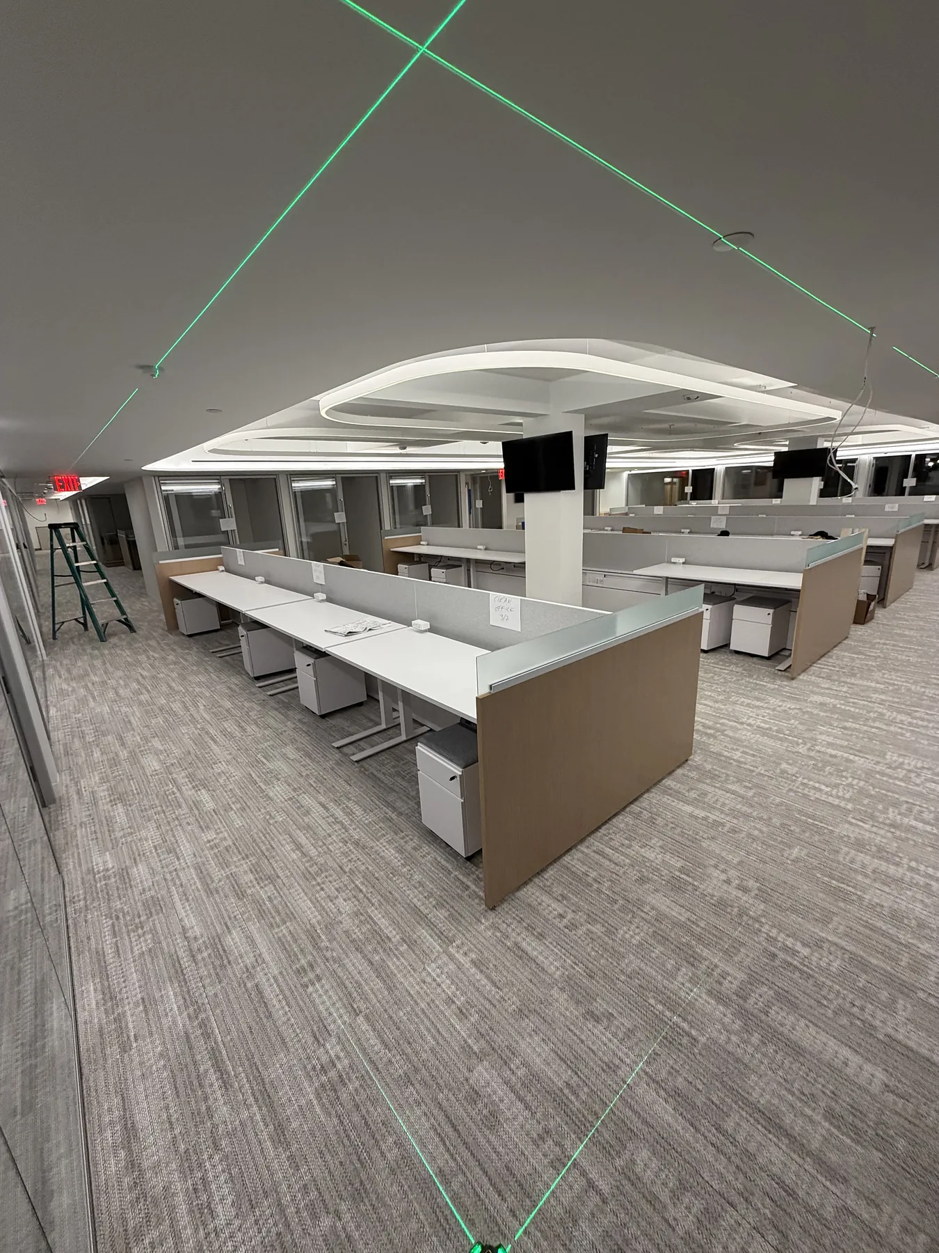 Open-plan office desks with laser level lines on the ceiling